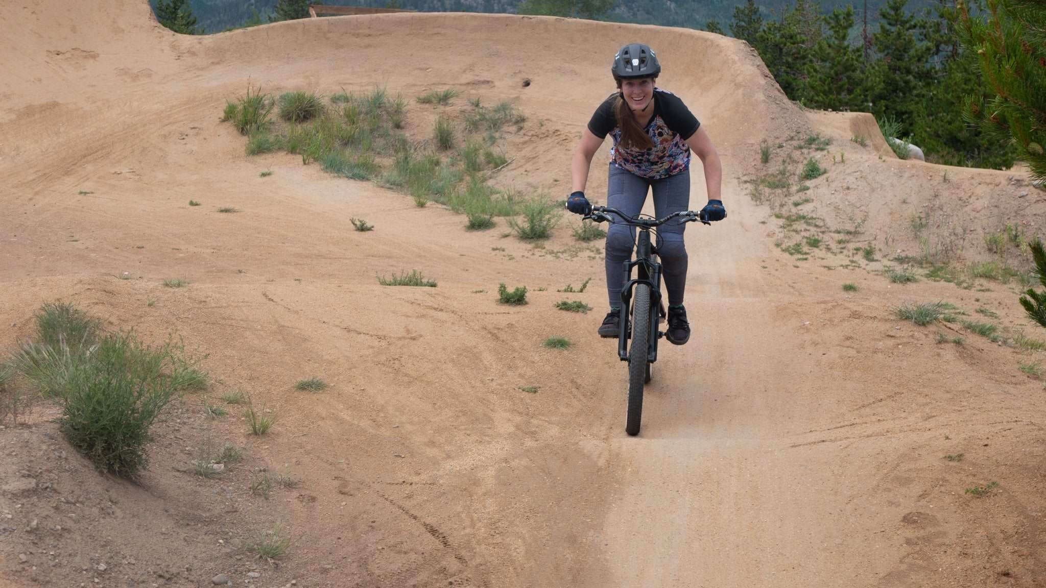 Rider wearing the Moxie Tee Jersey with graffiti design on a mountain biking trail.